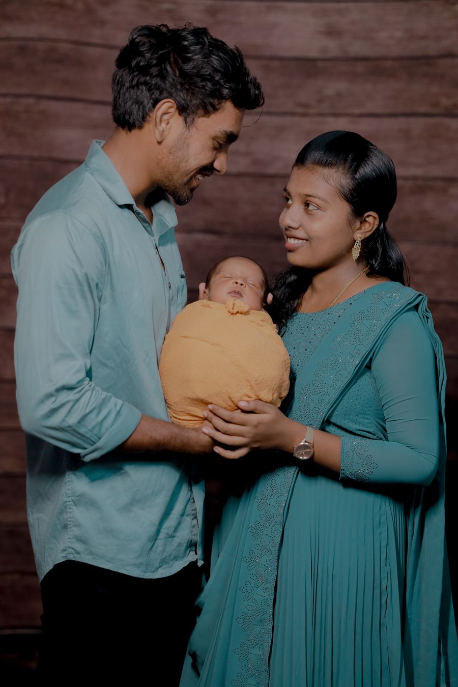 A young Kerala family smiling at their newborn baby